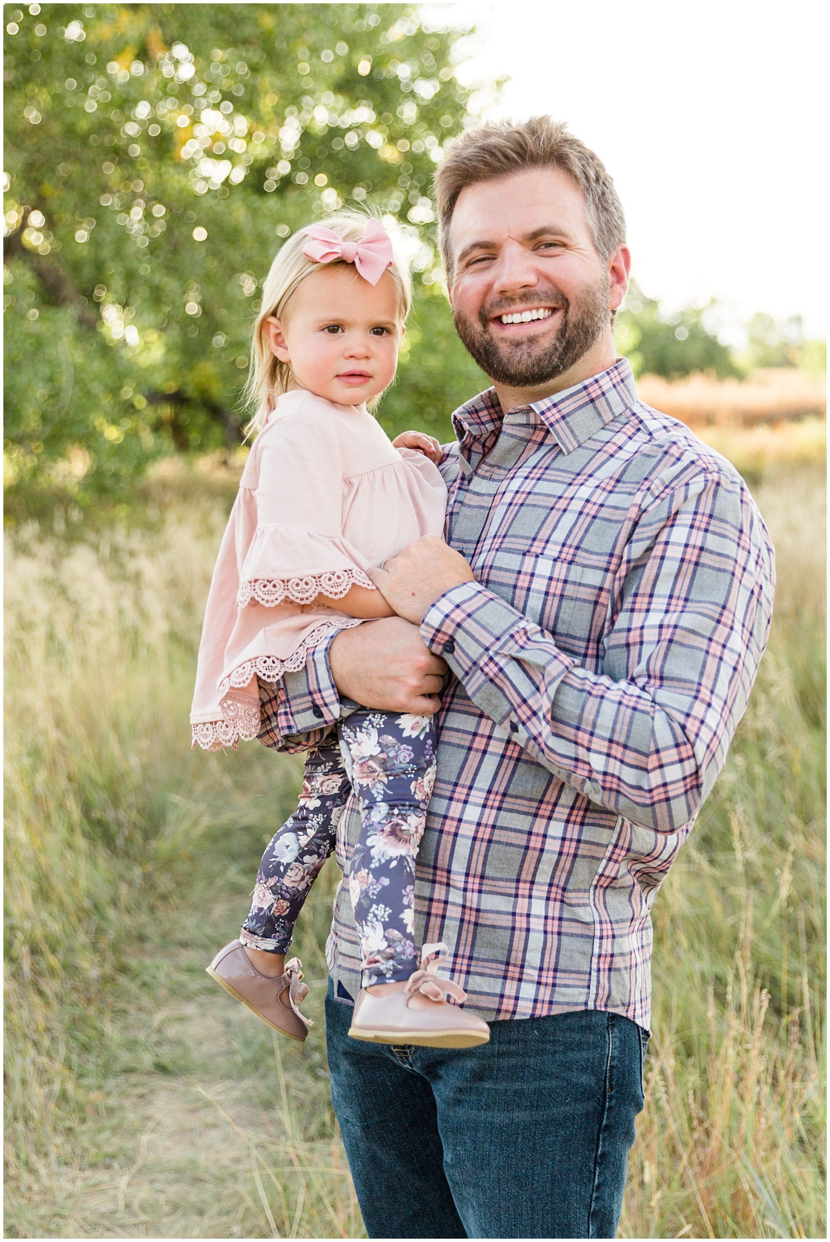 Photo of a father holding his daughter in a field during a fall mini photography session in Erie Colorado