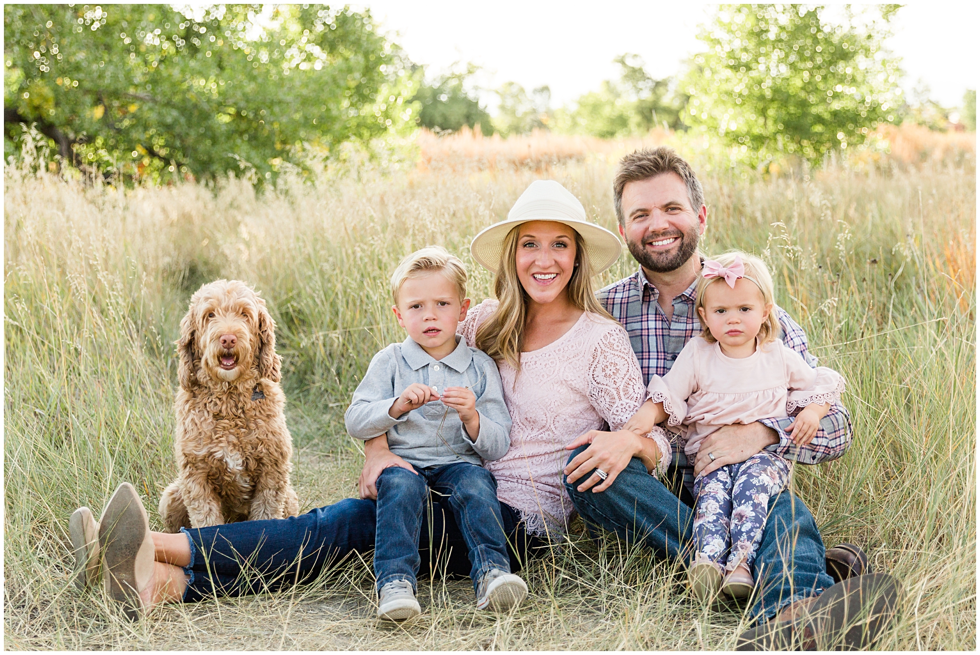 Photo of a young family and their dog sitting in a field during a fall mini photography session in Erie Colorado