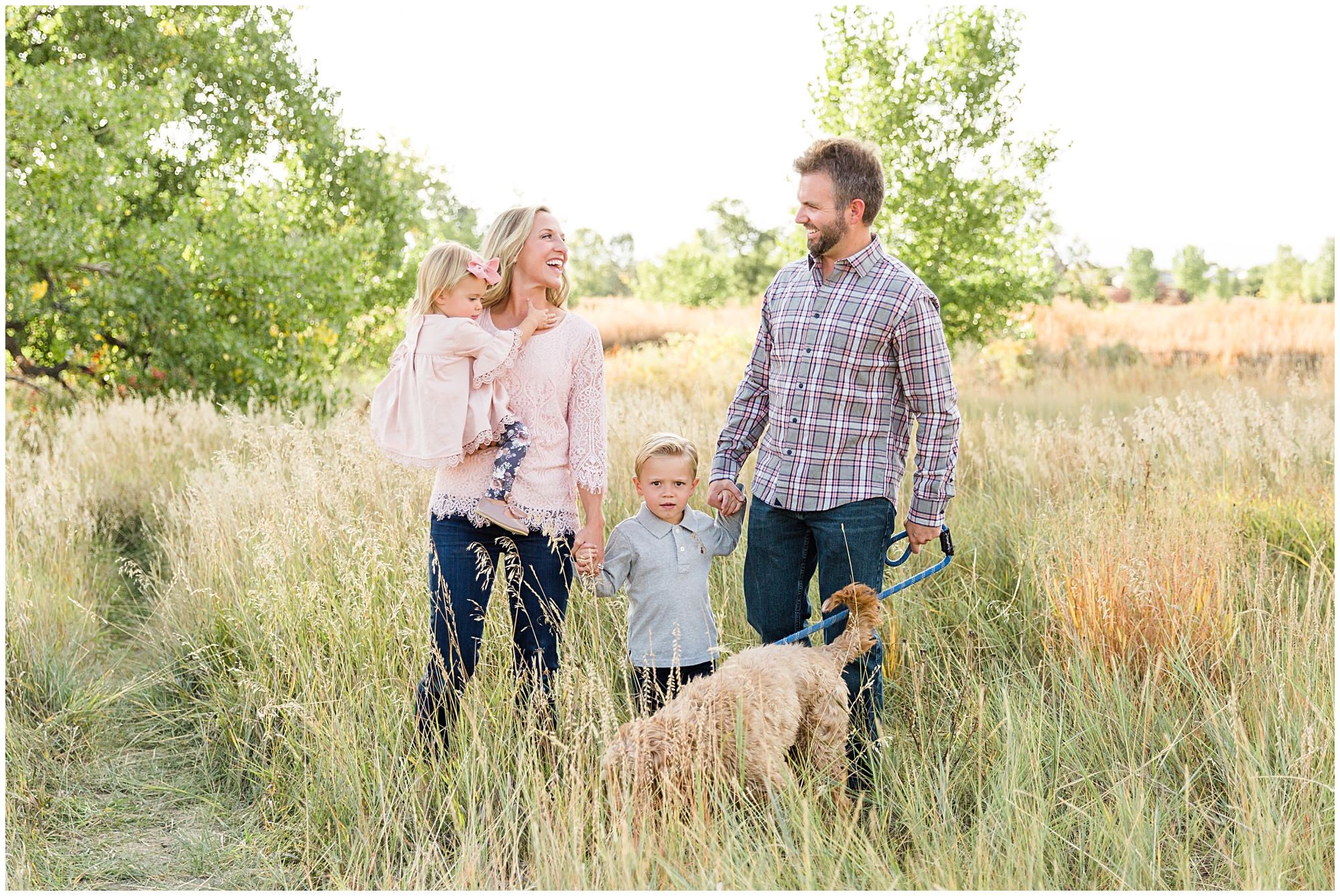 Photo of a young family and their dog walking in a field during a fall mini photography session in Erie Colorado