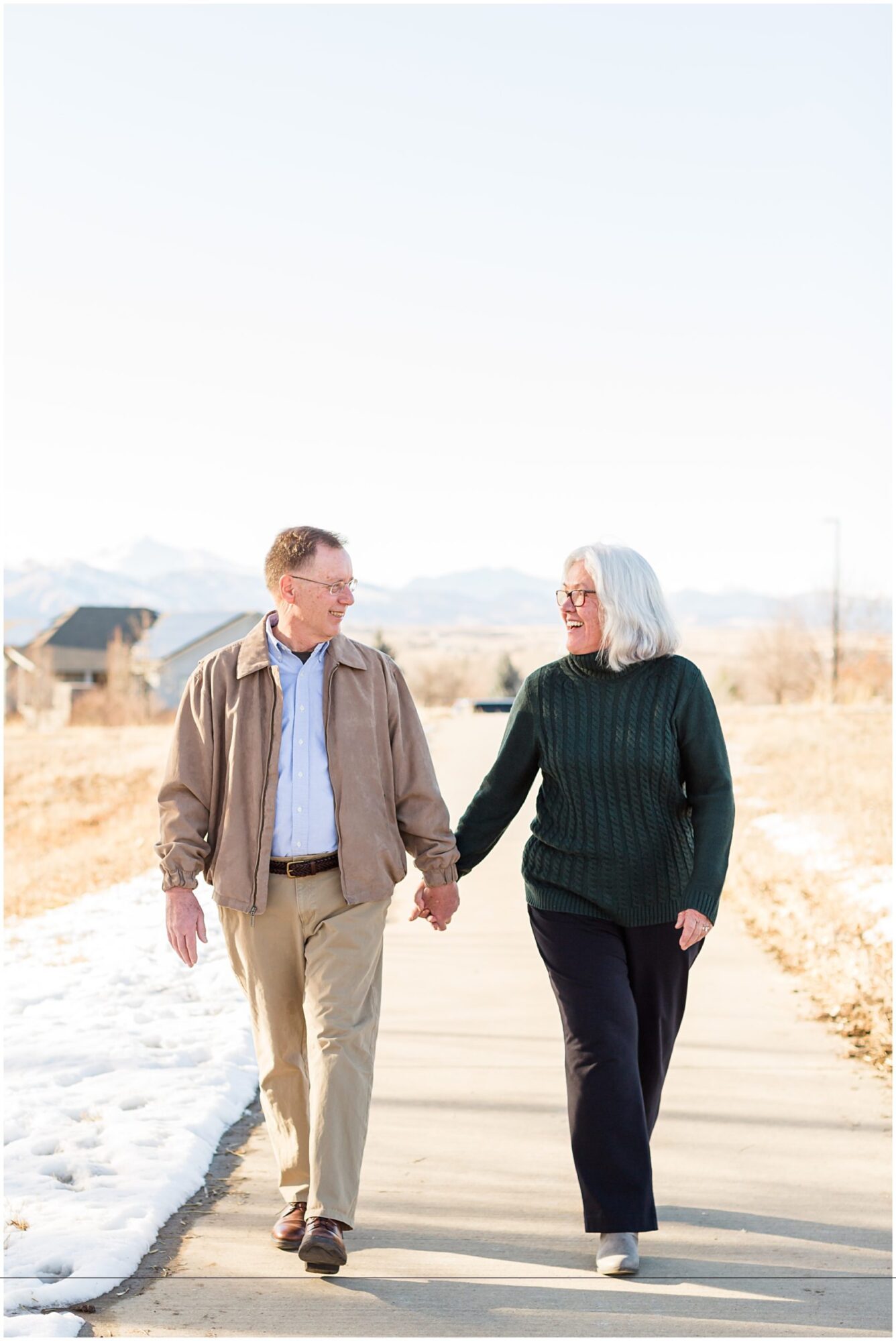 A grandmother and grandfather hold hands while walking along a trail during an outdoor portrait session in Erie Colorado