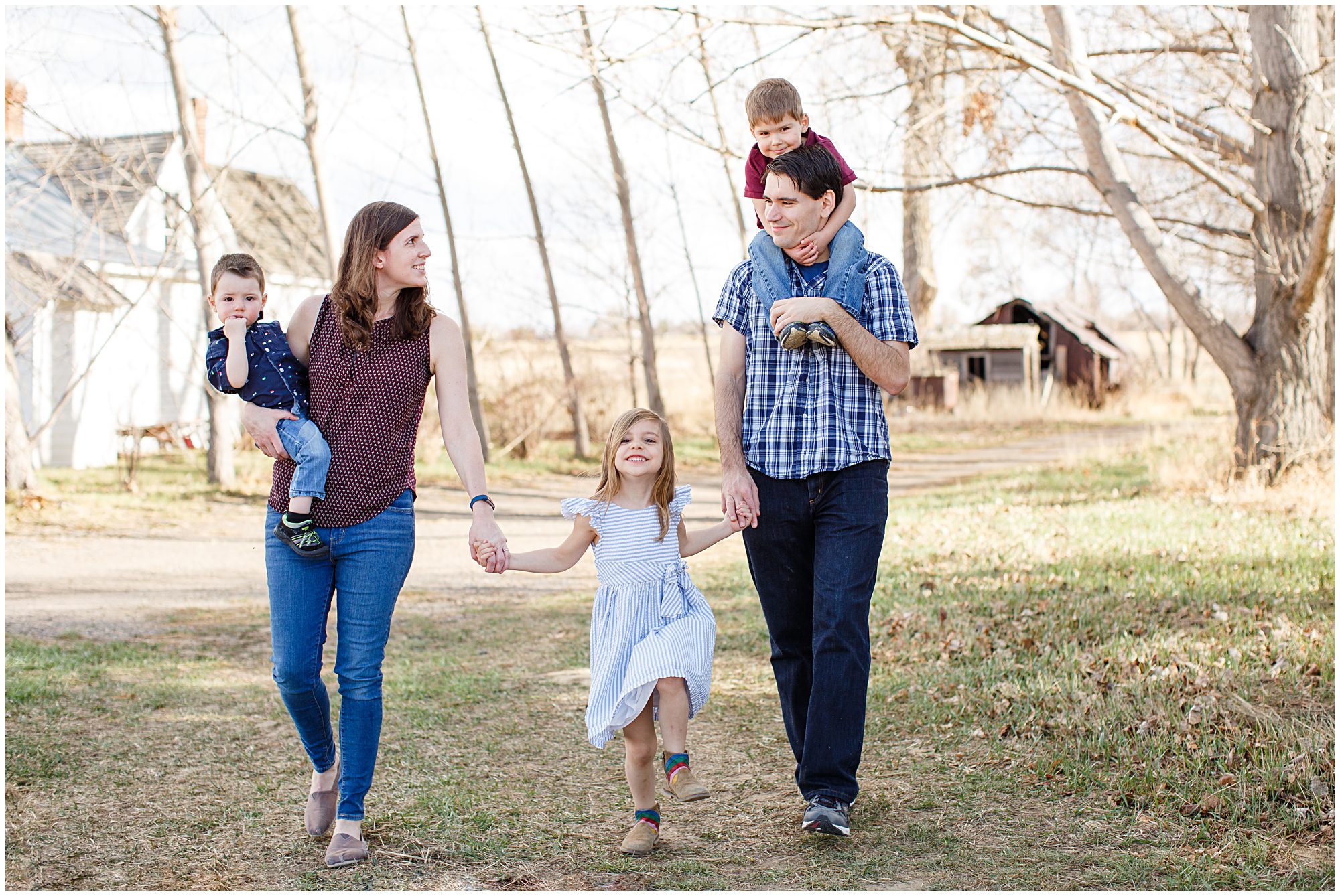 A young family hold hands as the walk along the edge of a field during an outdoor family photography session in Erie Colorado