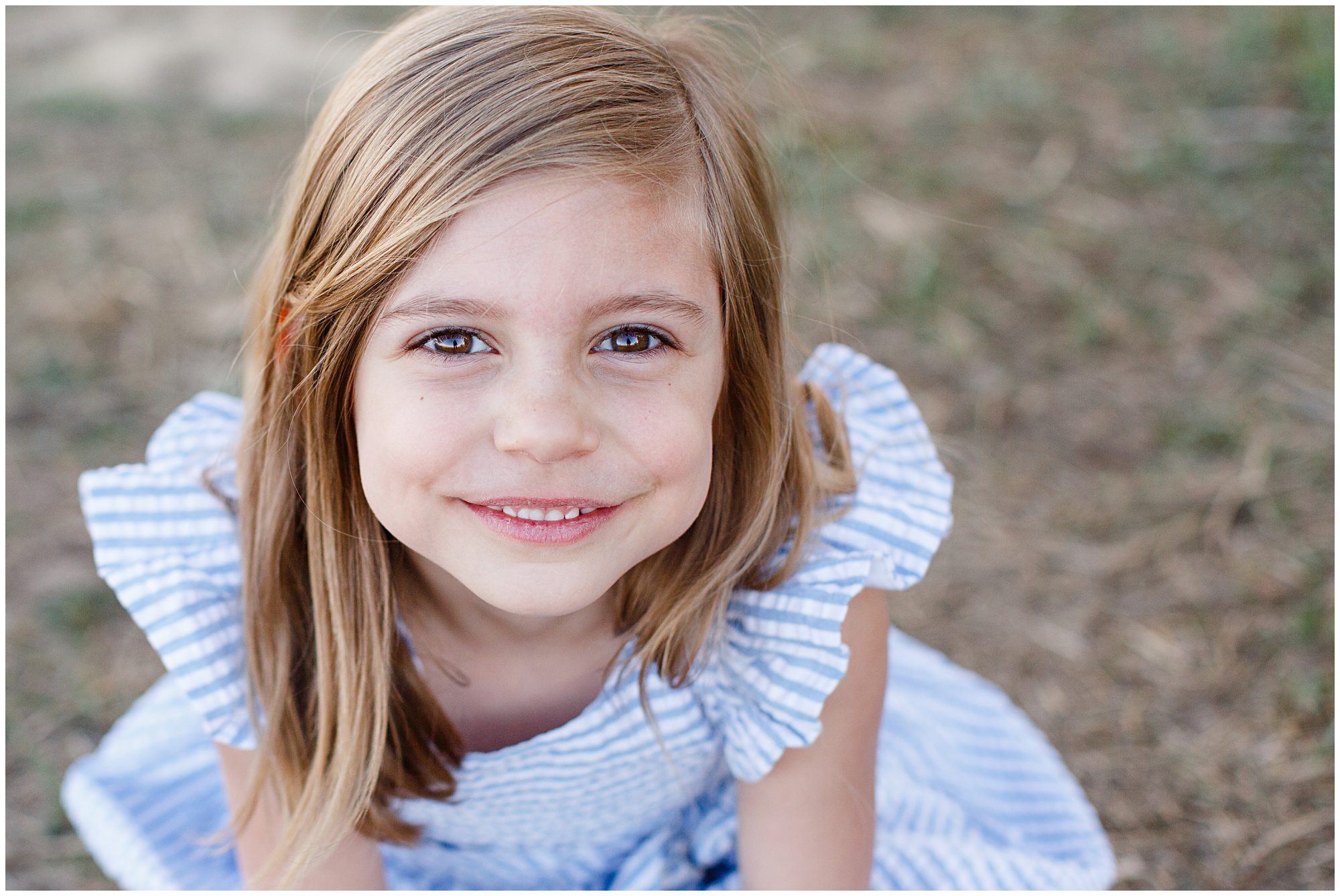 A young girl smiles sweetly at the camera during an outdoor family photo session in Erie Colorado