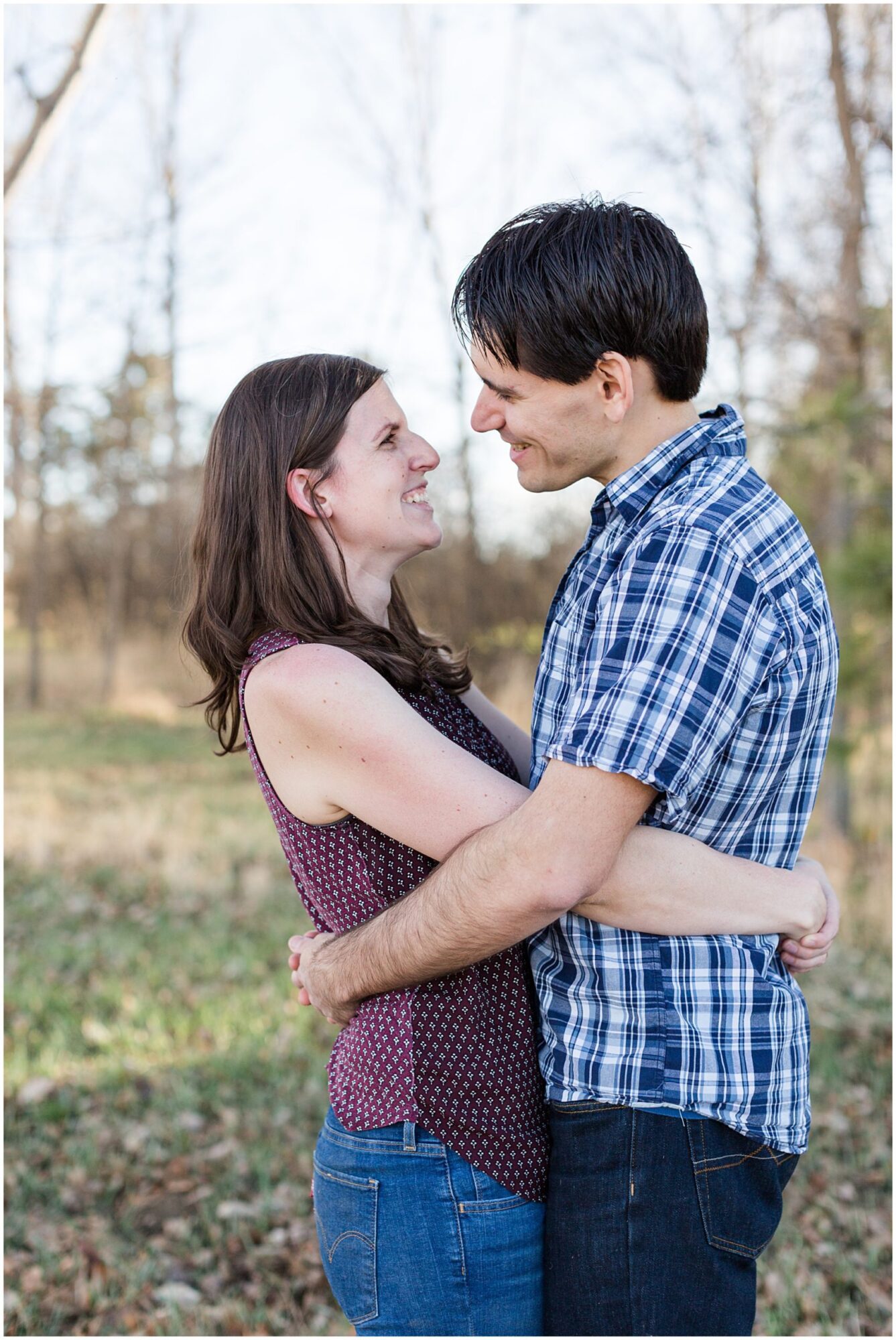 A young husband and wife embrace as they laugh into each others eyes during an outdoor family photography session in Erie Colorado