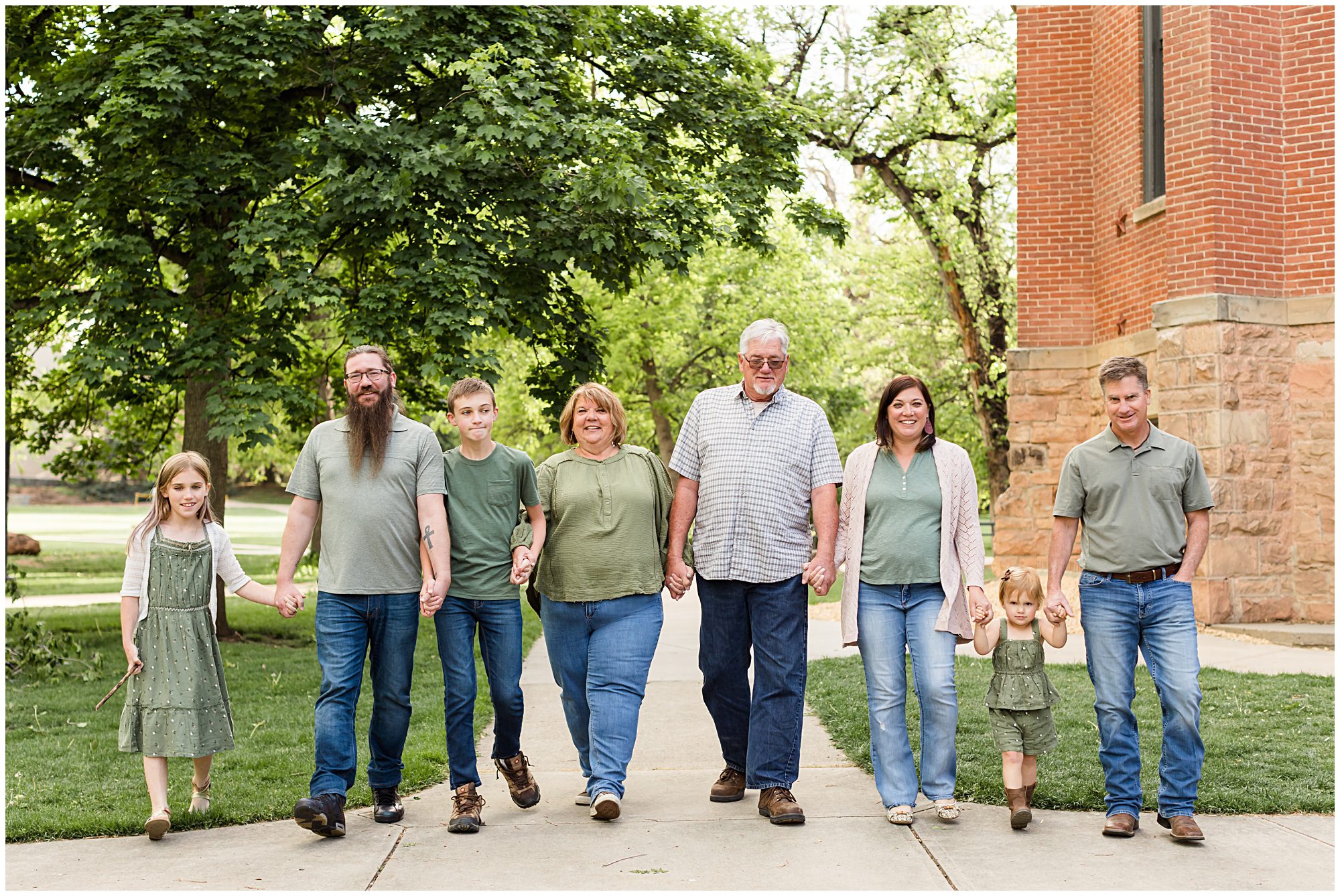 An extended family hold hands as they walk during an extended family session in Boulder