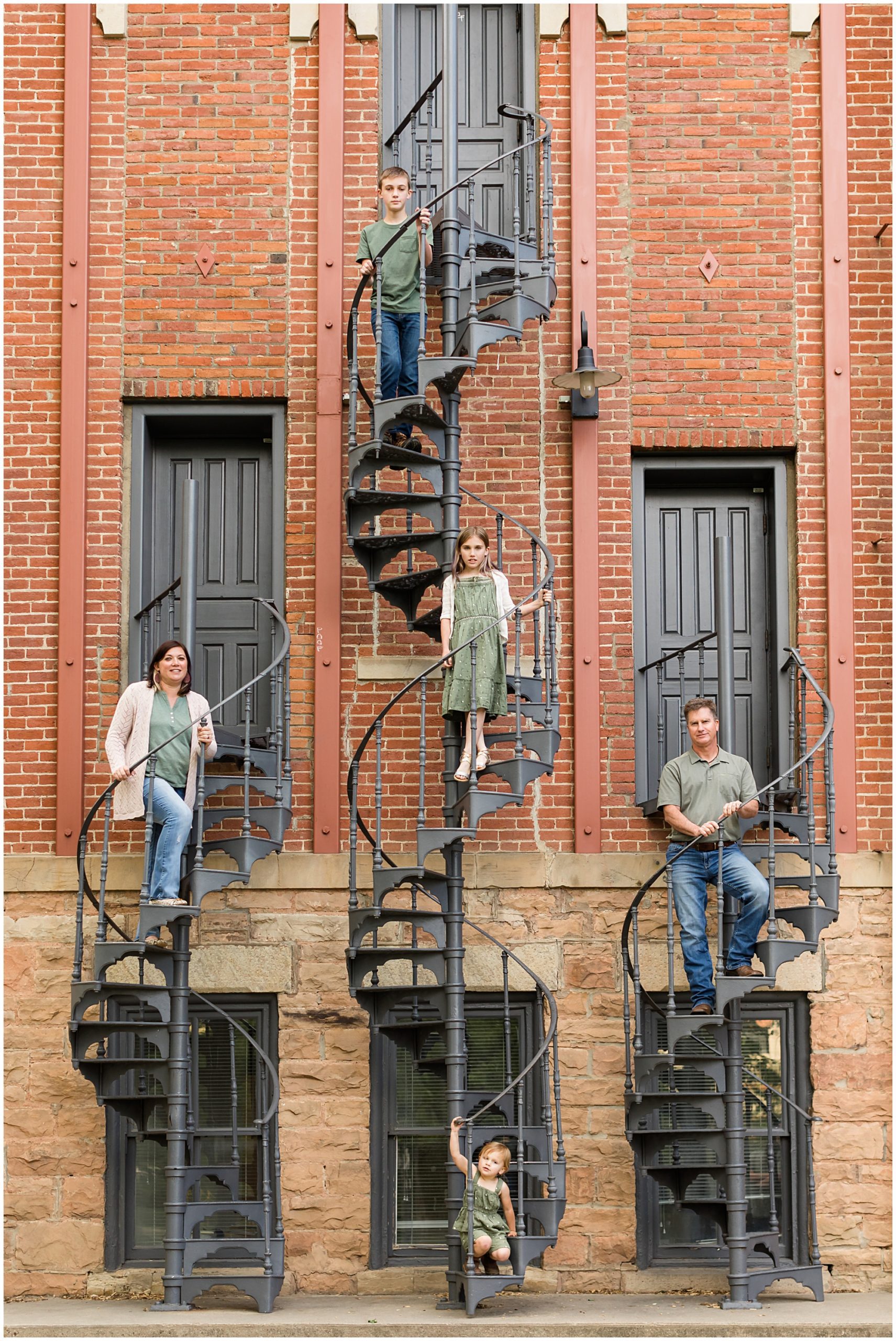 A family of five pose on a trio of curved iron staircases during a family photo session in Boulder
