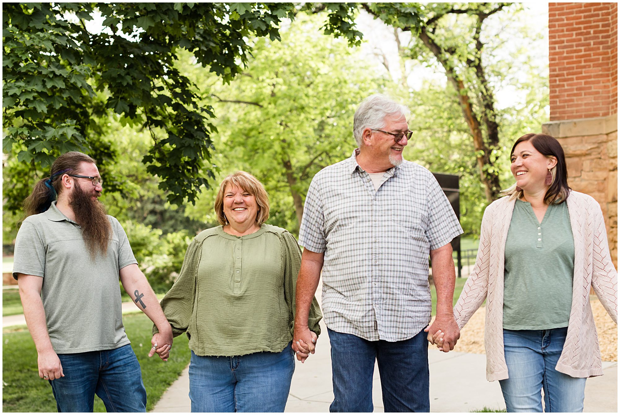 An extended family hold hands as they walk during an extended family session in Boulder