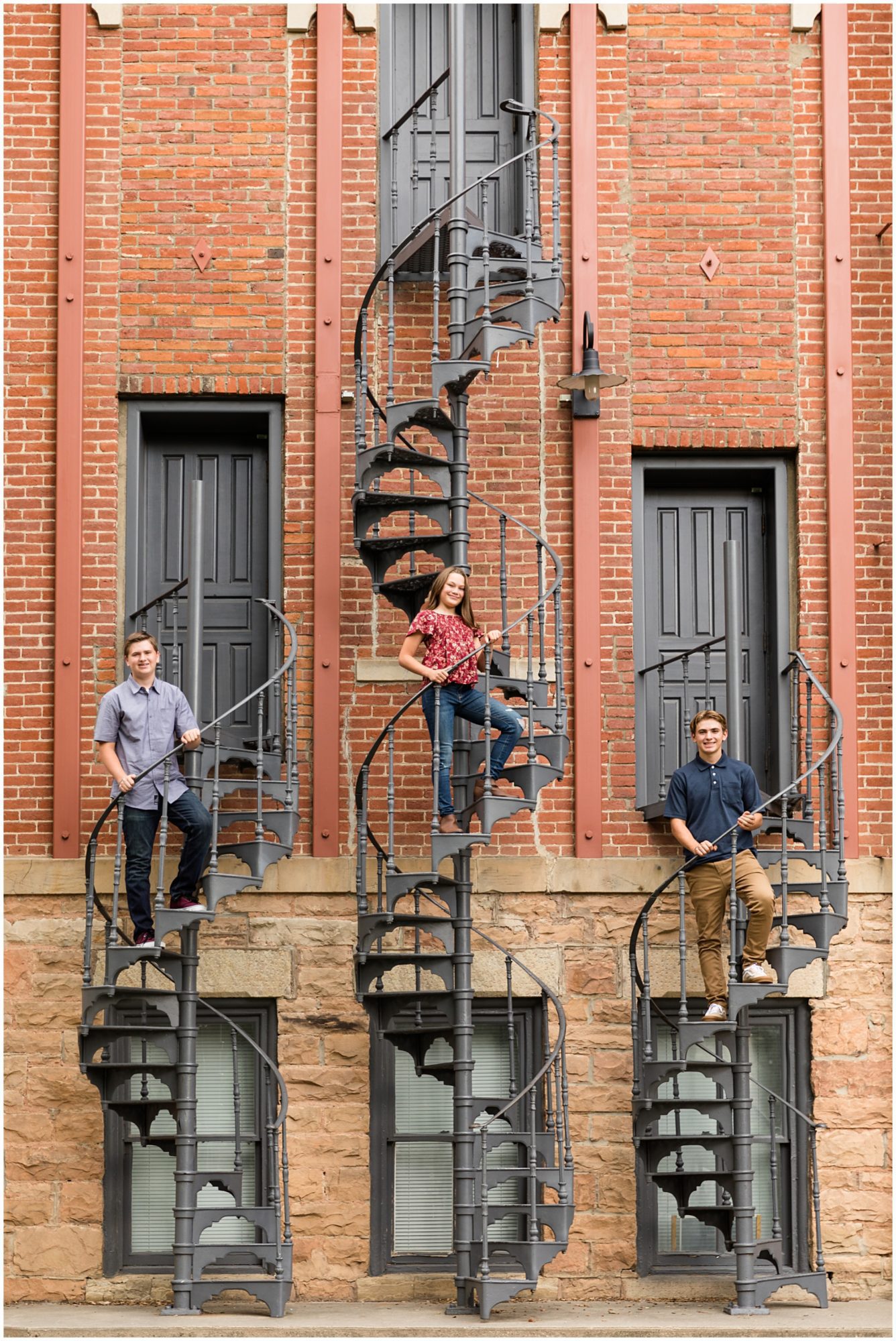 Three teenagers pose on spiral staircases during their family photography session