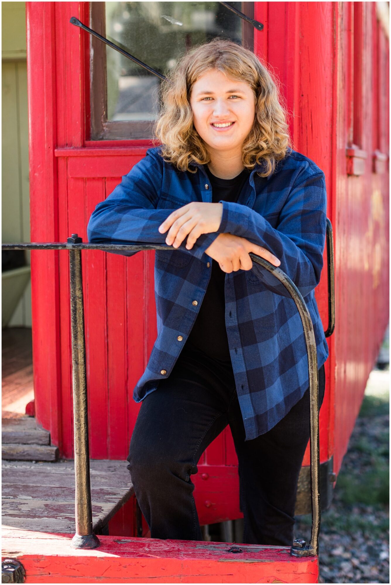 An Erie senior guy standing on a caboose during his senior portrait session