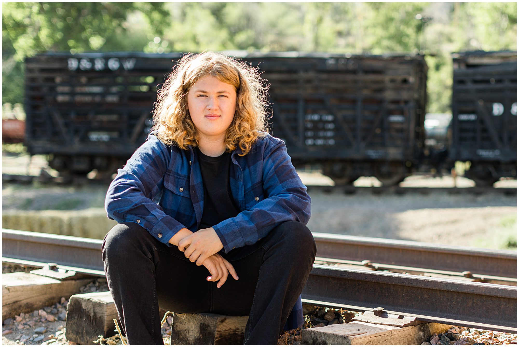 A high school senior guy poses in a train yard during his senior portrait session