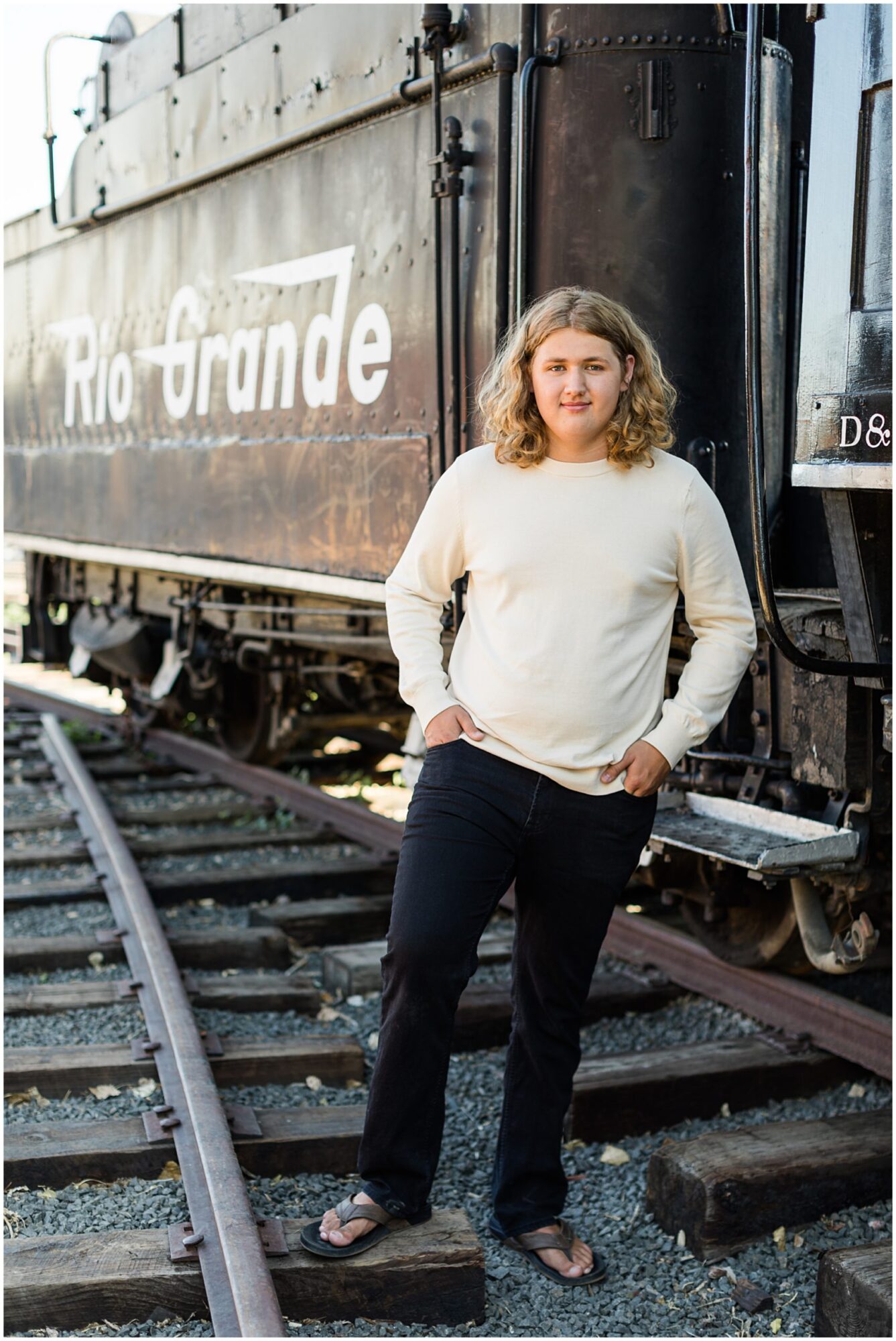 A high school senior guy poses in a train yard during his senior portrait session