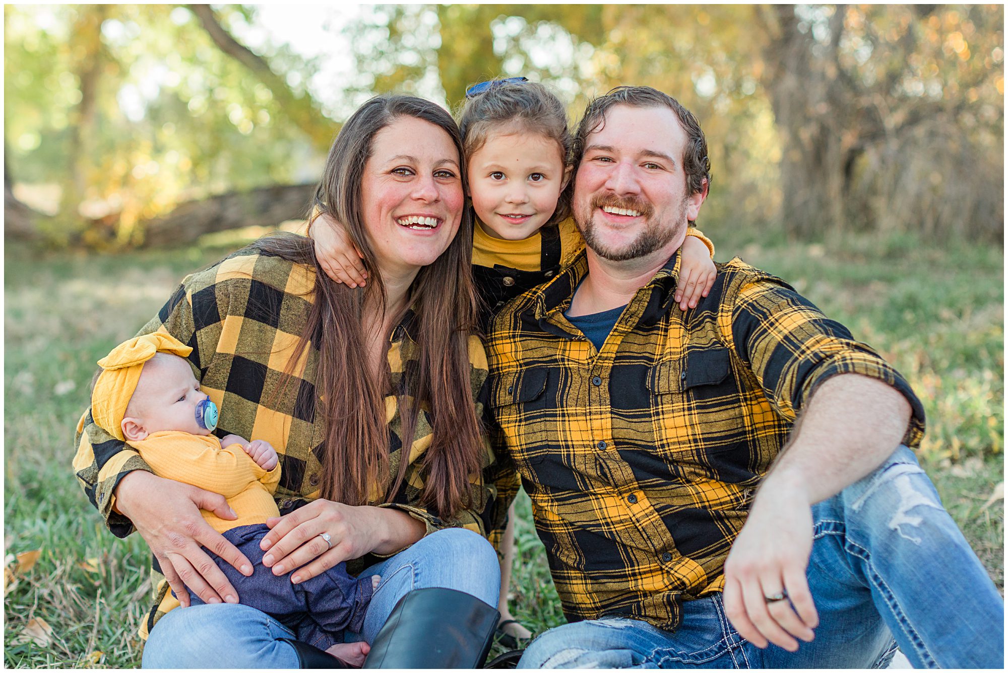 A mother and father cuddle their young daughter and new baby as they laugh at the camera during their fall mini session at Thomas Reservoir