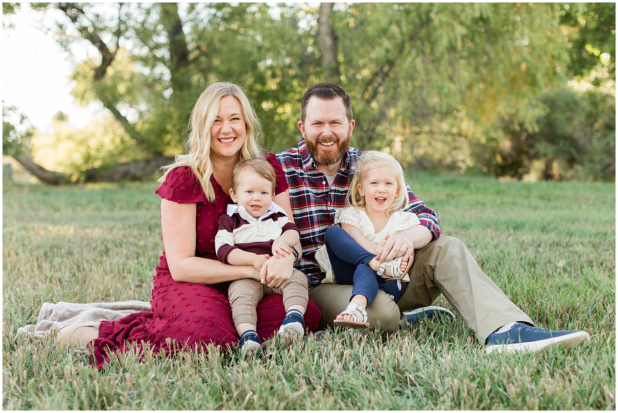 A mother and father cuddled with their two young children smile at the camera during their fall mini session at Thomas Reservoir