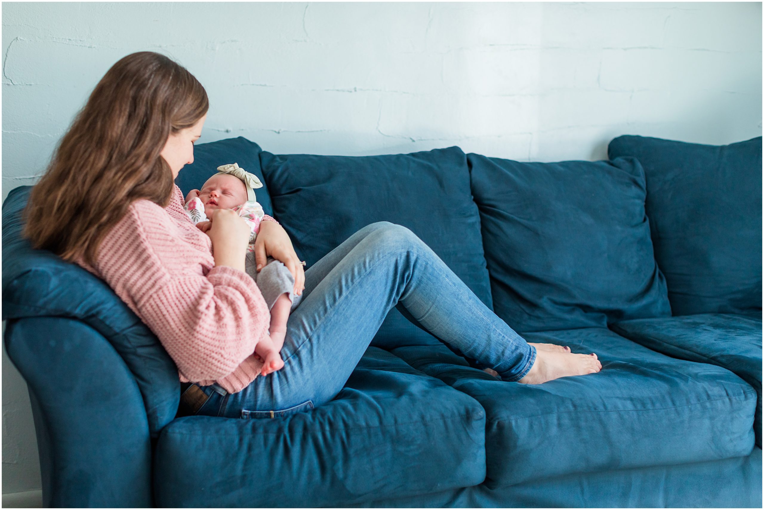 A candid photo of a new mom cradling her sleeping baby girl during an in-home newborn session by Theresa Pelser Photography