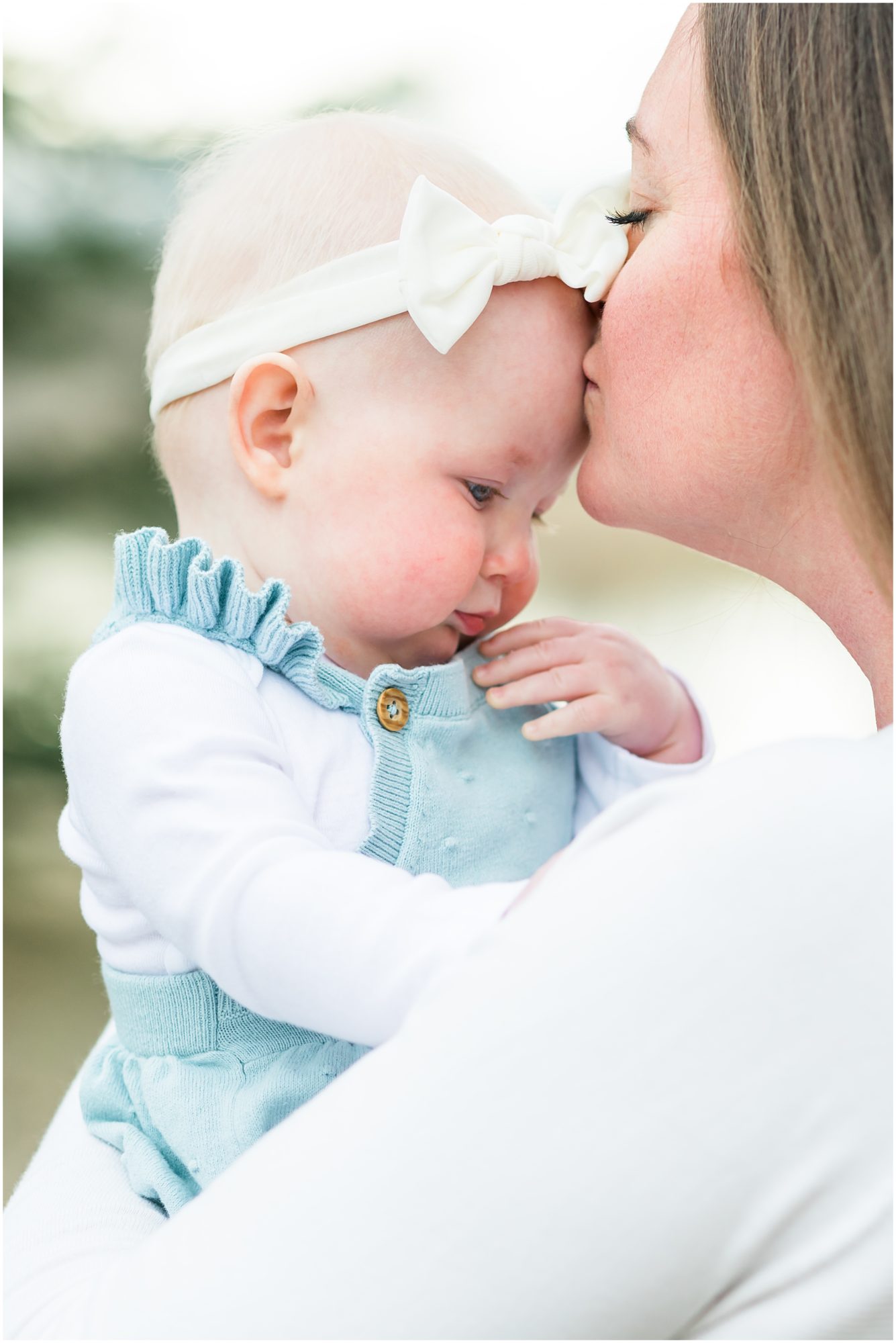 A photo of a mother kissing her baby girl's forehead captured during their family session with Theresa Pelser Photography