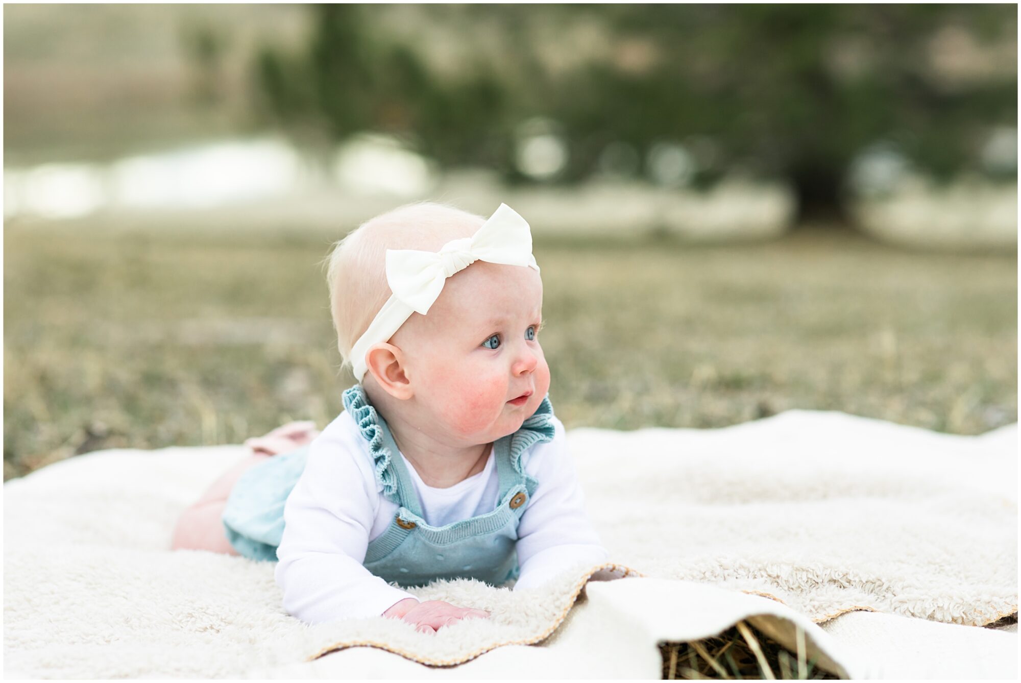 A baby girl lying on a blanket looks off camera during a family session with Theresa Pelser Photography