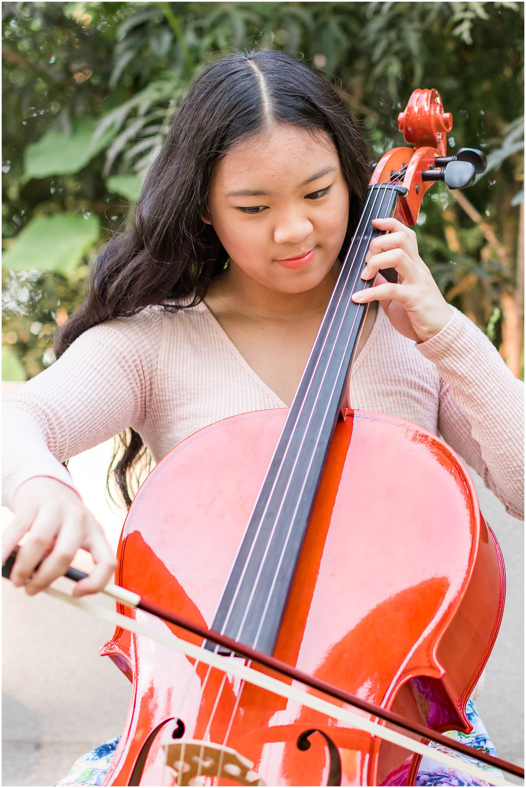 family-session-gyorffy-boulder_0004 High school senior girl smiling and posing with her cello among vibrant flowers in the garden of Callahan House