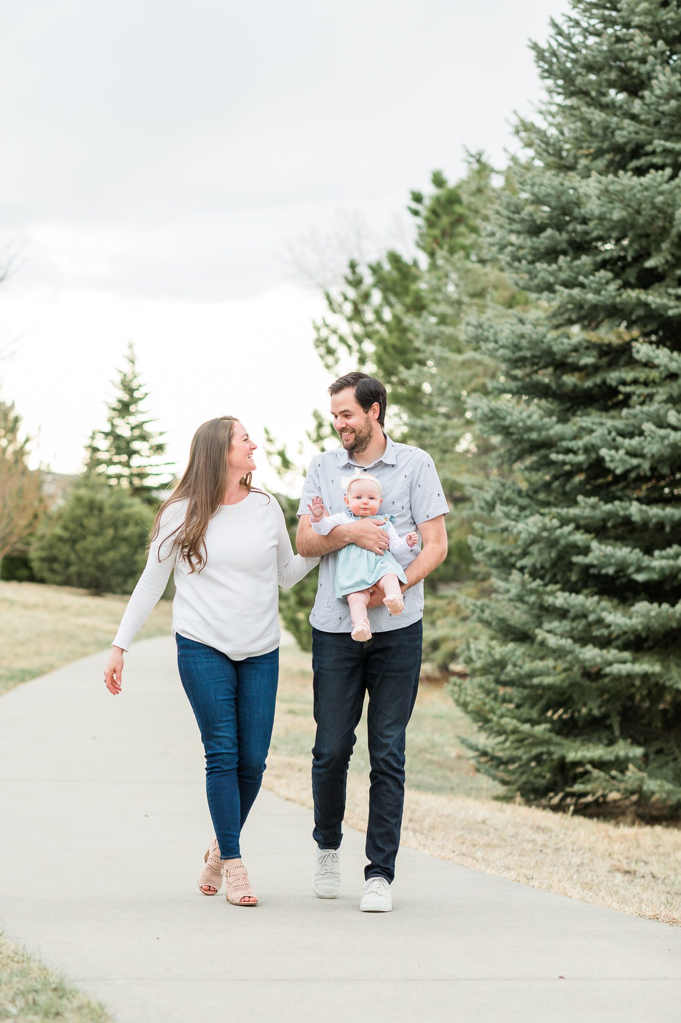 Parents and an infant smiling together in a park during a family session with an Erie family photographer.