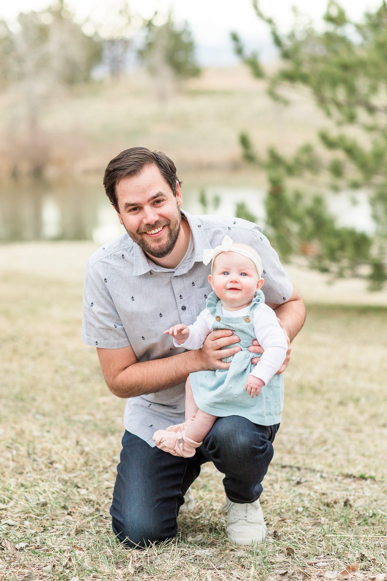 Father smiling while holding his young daughter outdoors during a family photo session near Erie, Colorado.