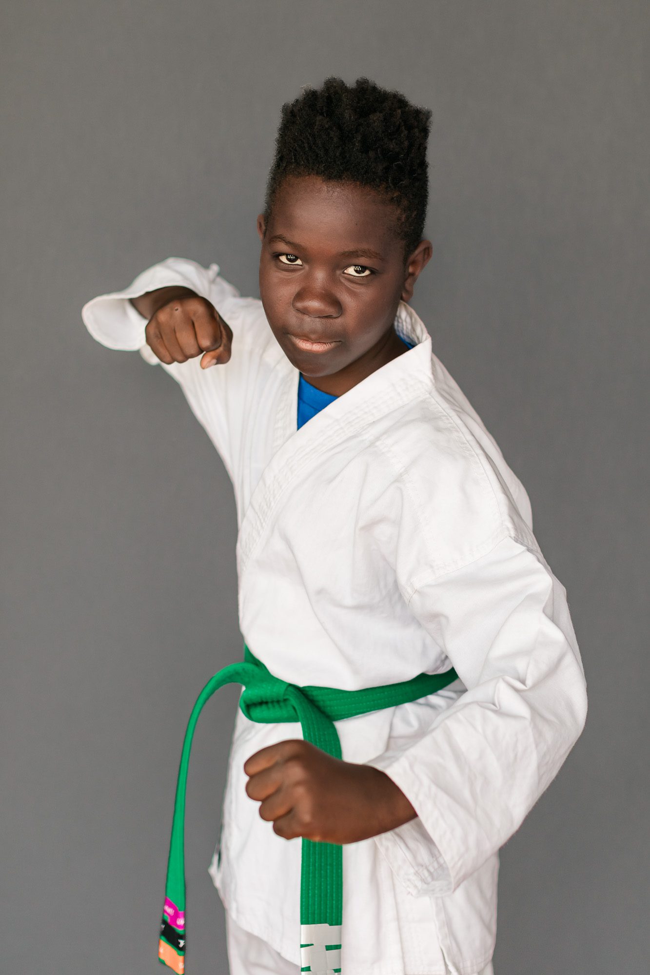 Boy in martial arts uniform and green belt posing for picture day at Schilz Martial Arts in Lafayette, Colorado.