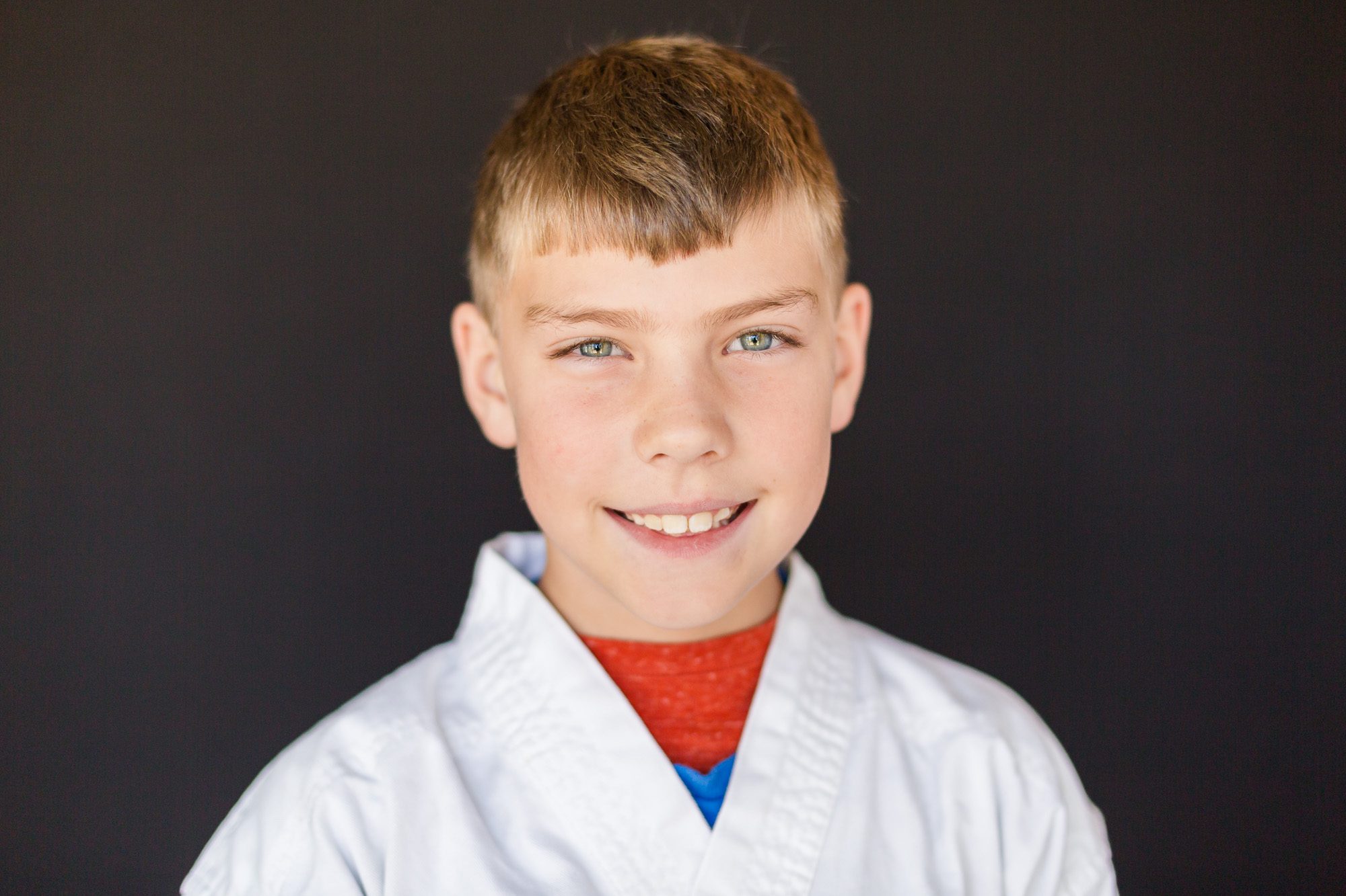 Close up of a young boy in martial arts gear smiling during picture day at Schilz Martial Arts in Lafayette, Colorado.