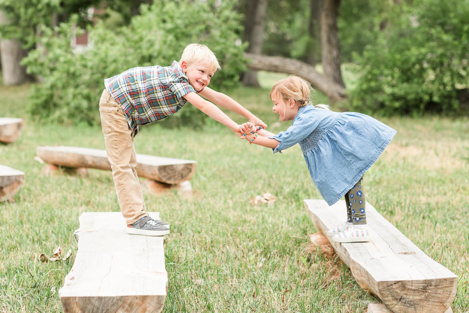 Fall mini session at Thomas Reservoir in Erie, Colorado—young brother and sister playing and balancing on wooden benches, sharing a joyful moment outdoors. Captured by Theresa Pelser, Erie family photographer.