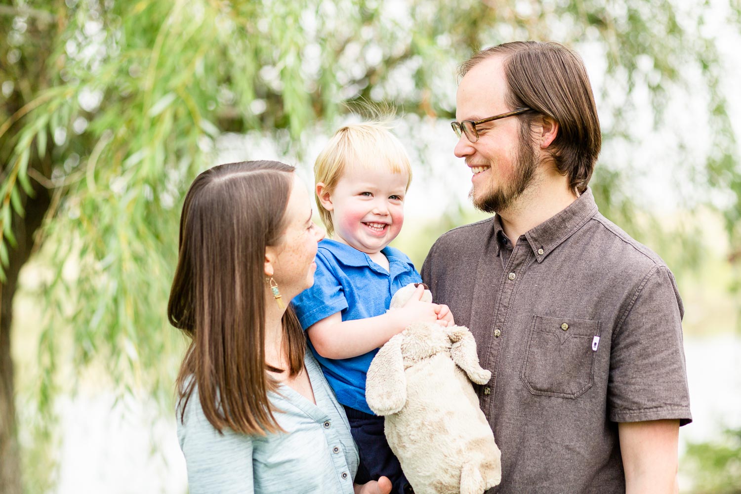 Family photo session in Broomfield Colorado with parents smiling at their toddler in a natural, connected moment