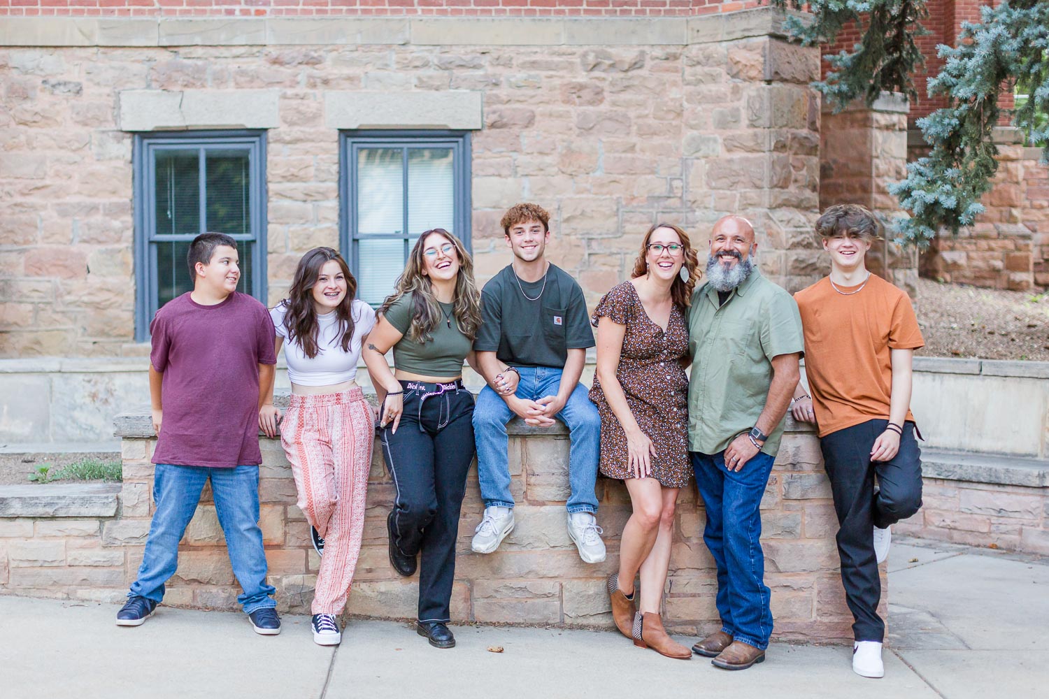 Family session in Boulder, Colorado—parents and four teenagers smiling and relaxed, standing and sitting along a historic brick building. Captured by Theresa Pelser, Boulder family photographer.