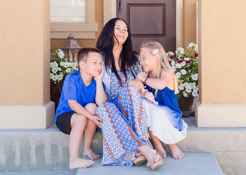 Mom and kids on front steps in soft blues and patterned outfit ideas for at-home family pictures.