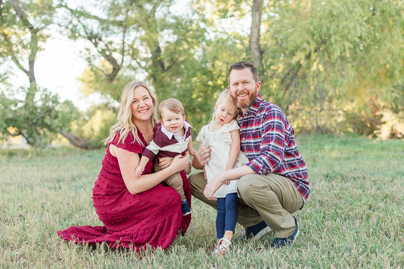 Family wearing a textured maroon dress and plaid shirt paired with cream and blue for a classic example of what to wear for fall family photos.