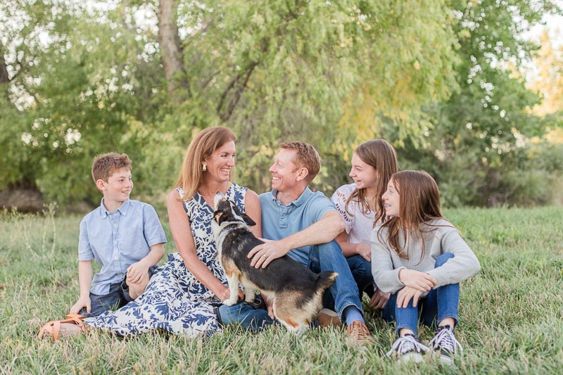 Family with dog sitting on grass in floral prints and cool tones - personalized ideas for what to wear for fall family photos