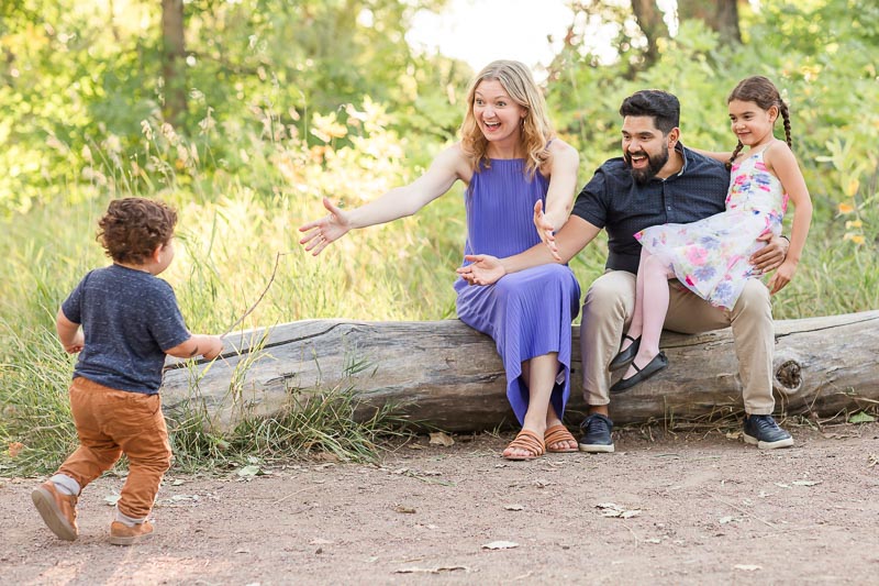 Family of four with mom in purple dress, dad in neutrals, and kids in florals and neutrals for visually interesting and coordinated family photo outfits.