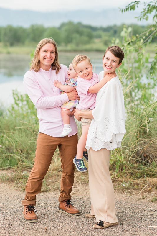 Family of four wearing dressy outfits in cream, pink, and camel color pallet for summer family photos.