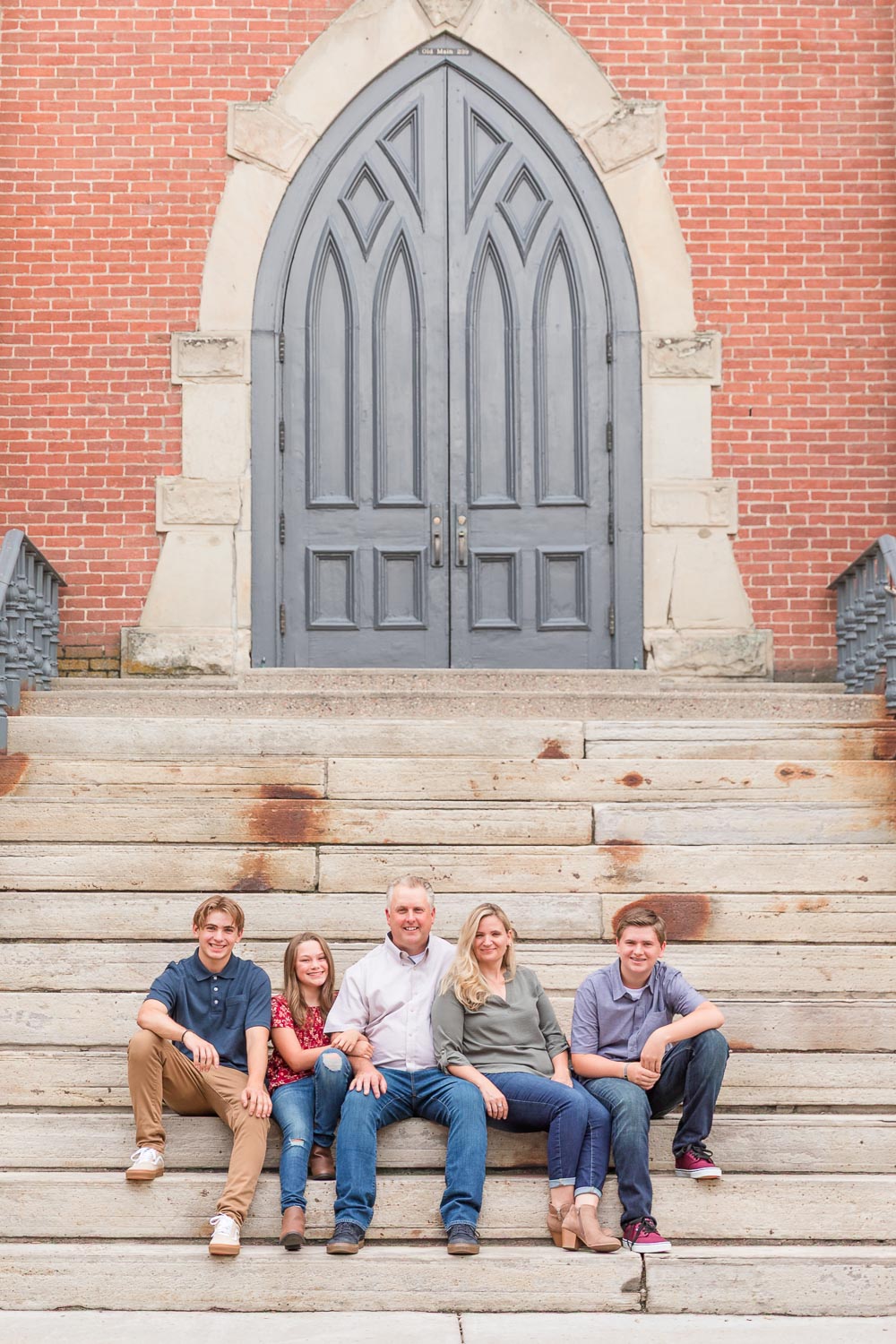Family of five sitting on stone steps during a photo session in Boulder, Colorado—parents and three teens relaxed and smiling together. Captured by Theresa Pelser, Boulder family photographer.