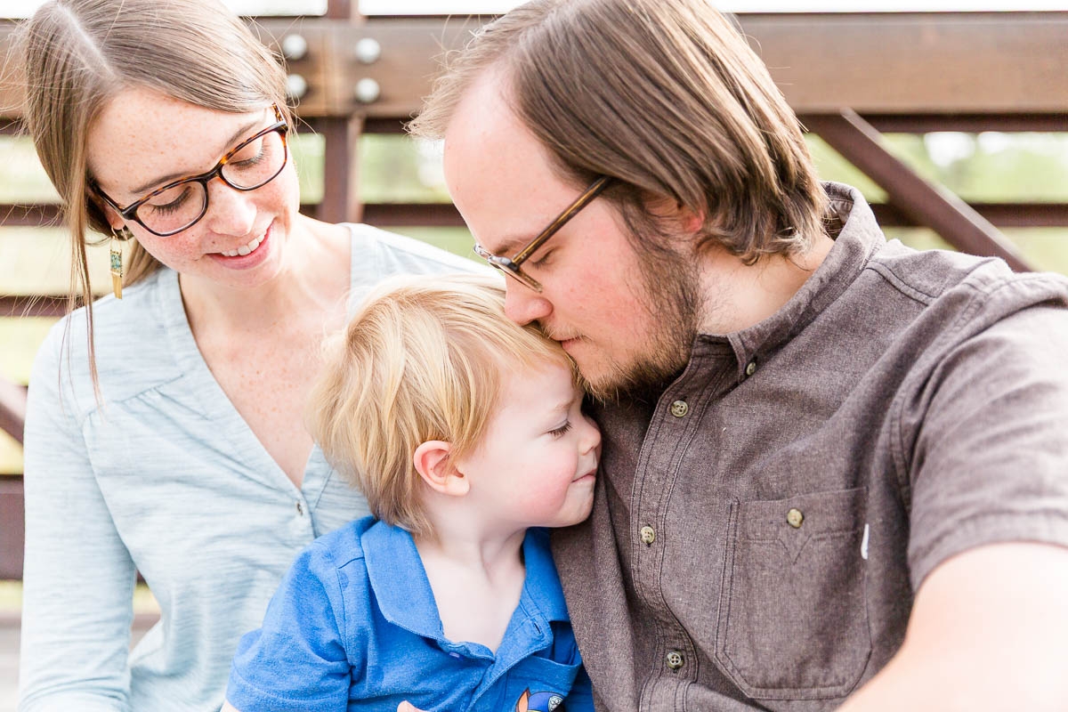 Young boy snuggled close between their parents during a family photo session