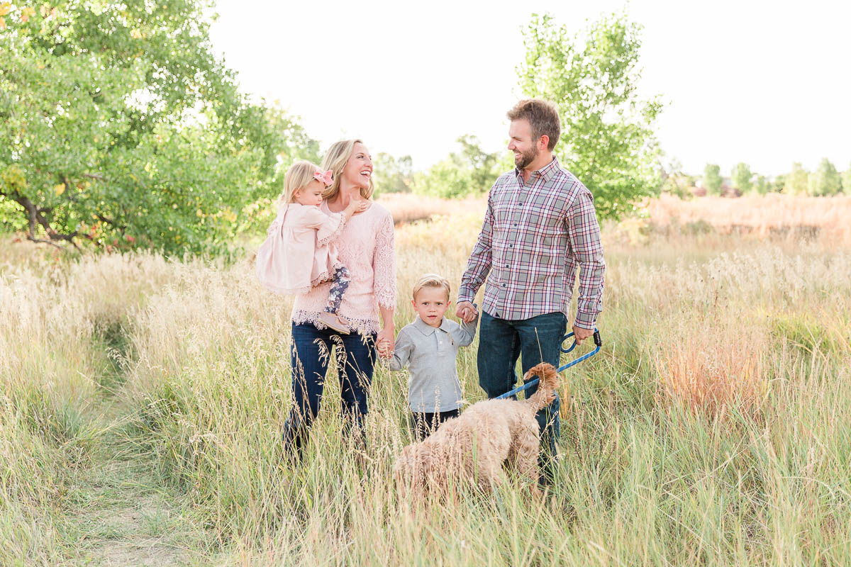 Family walking together through tall grass during an outdoor mini session.