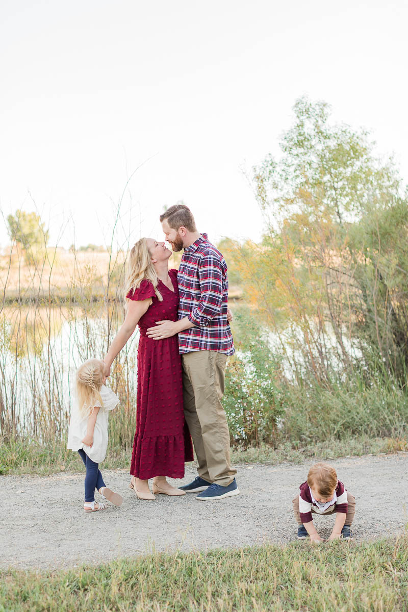 Young child standing apart while family members interact nearby during an outdoor family photo session