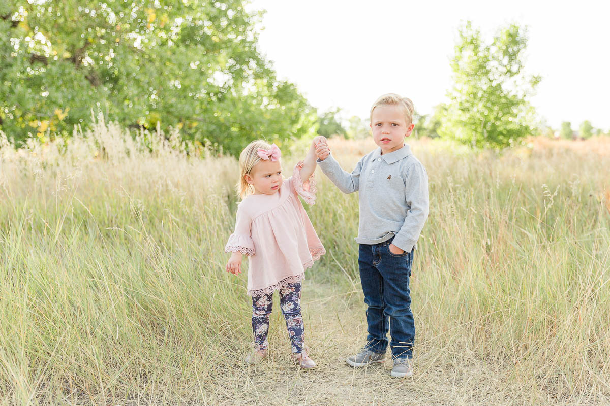 photo-shoot-01 Young brother and sister standing together in tall grass during an outdoor family mini session.